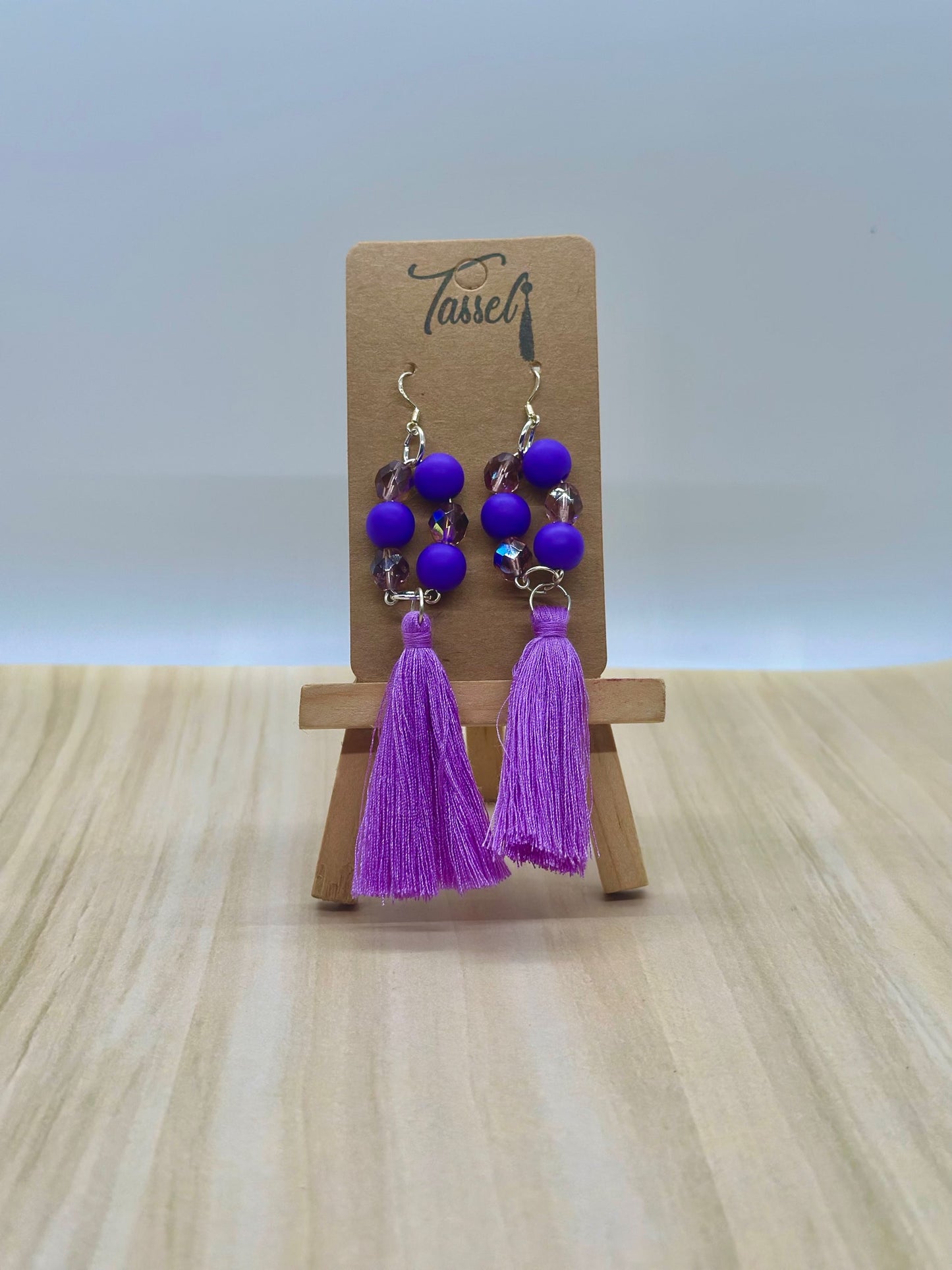 Purple circular dangle earrings with bright monochromatic beads and hanging tassel in multiple colors.