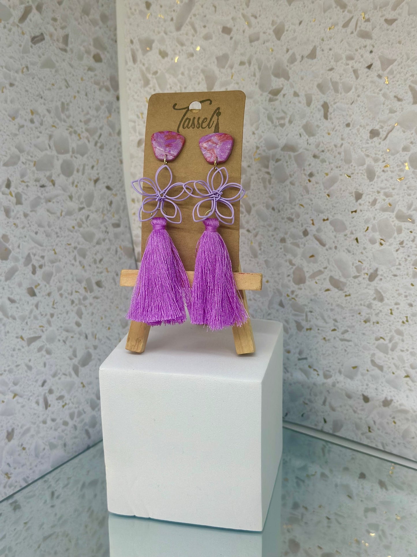 Flora tassel earrings featuring a delicate wire flower embellishment, bold polymer clay accents, and bright tassels in vibrant colors.