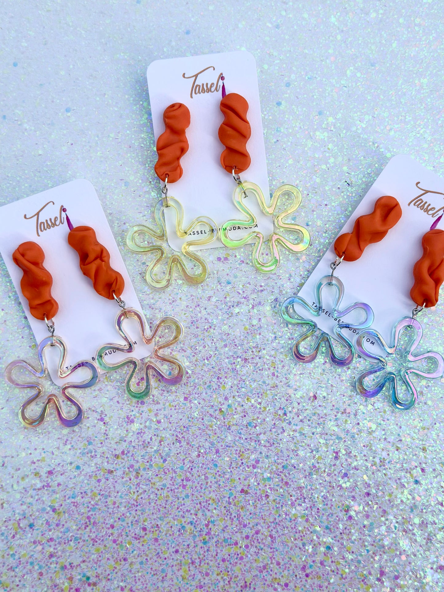 Statement handcrafted earrings featuring bright orange clay and iridescent flower