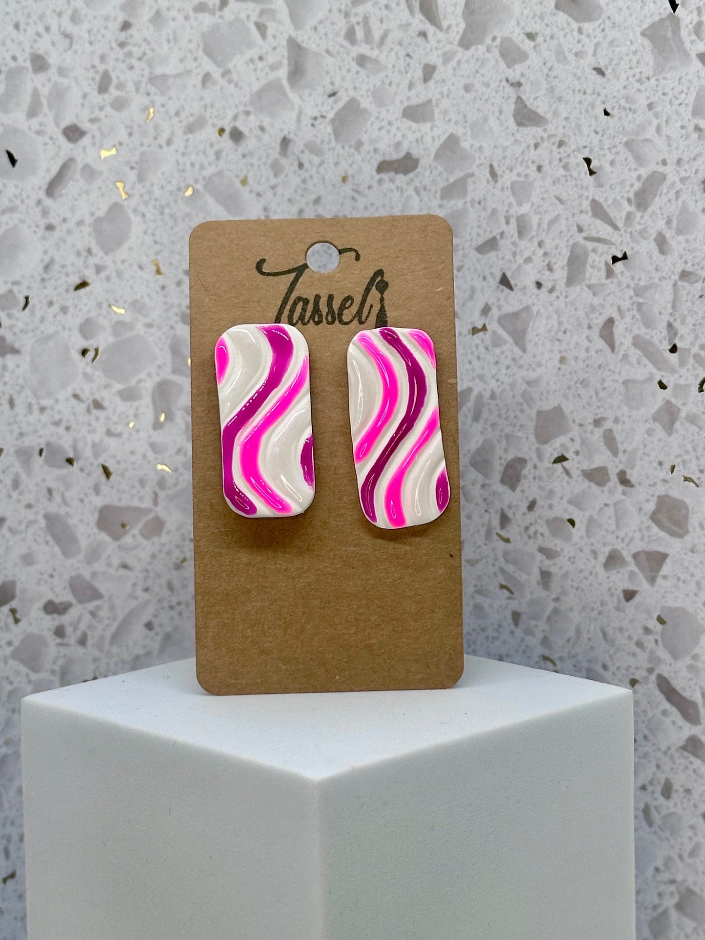 Close-up of Nola polymer clay stud earrings featuring a white base with colorful swirls and a glassy resin coating.