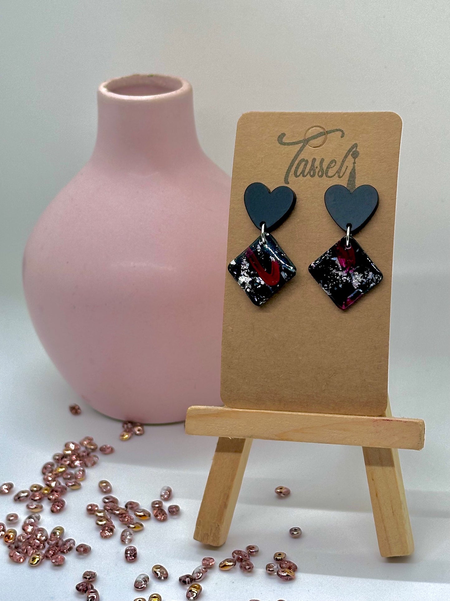 Passion dangle earrings handcrafted in black and red polymer clay with silver flecks, resin finish, and heart-shaped earring post.