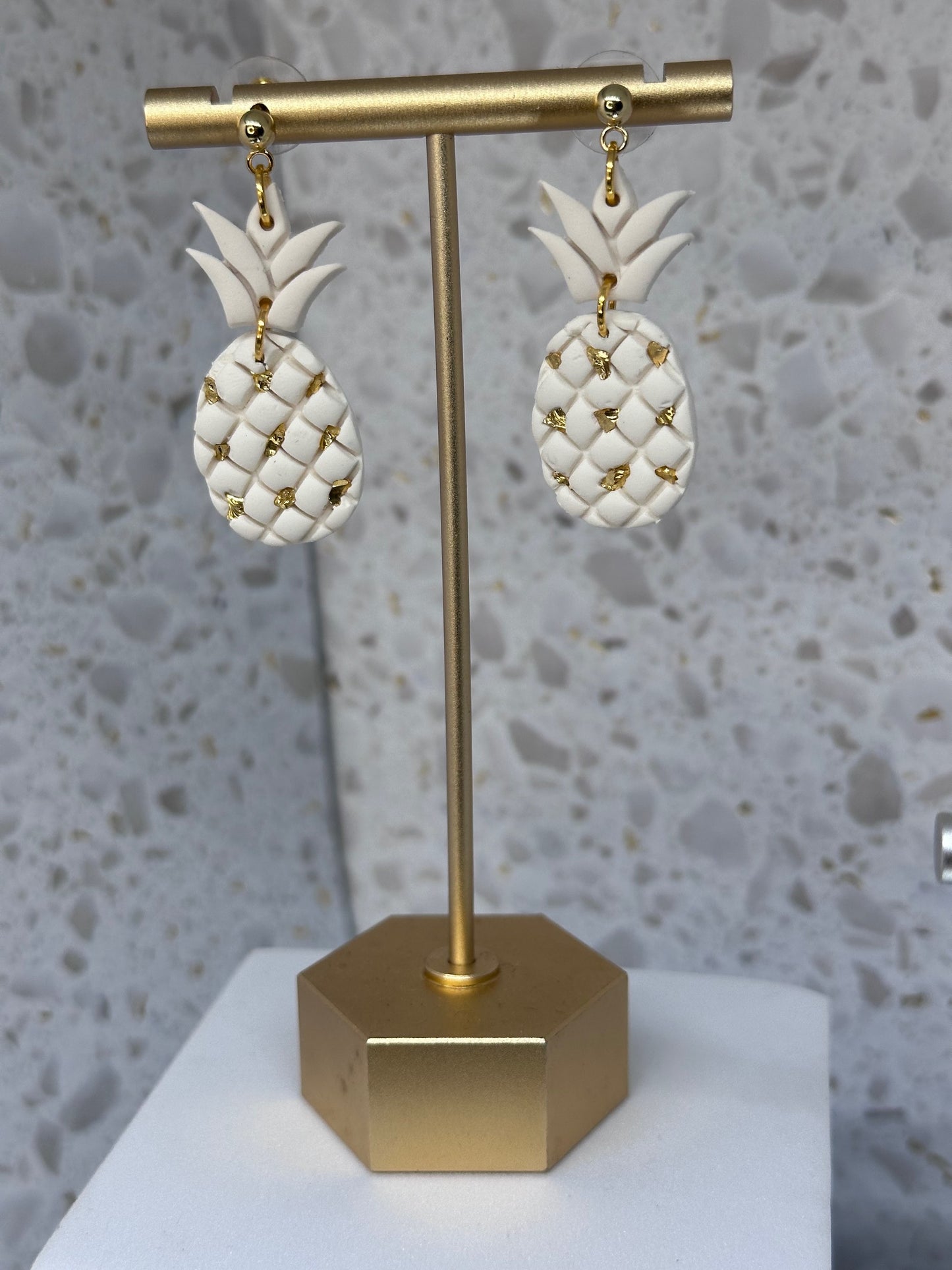 Pineapple-shaped polymer clay dangle earrings with shimmering gold shattered stone embellishments, inspired by tropical island style.