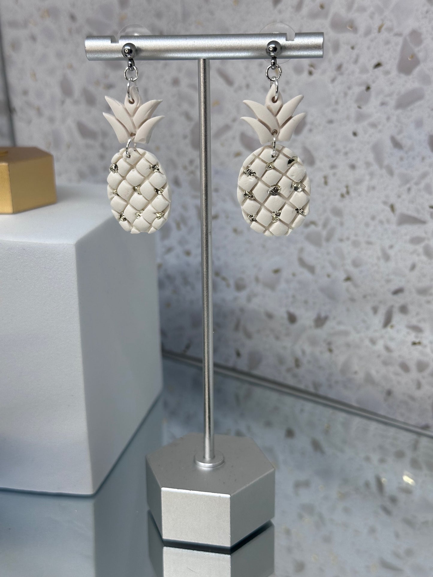 Pineapple-shaped polymer clay dangle earrings with shimmering silver shattered stone embellishments, inspired by tropical island style.