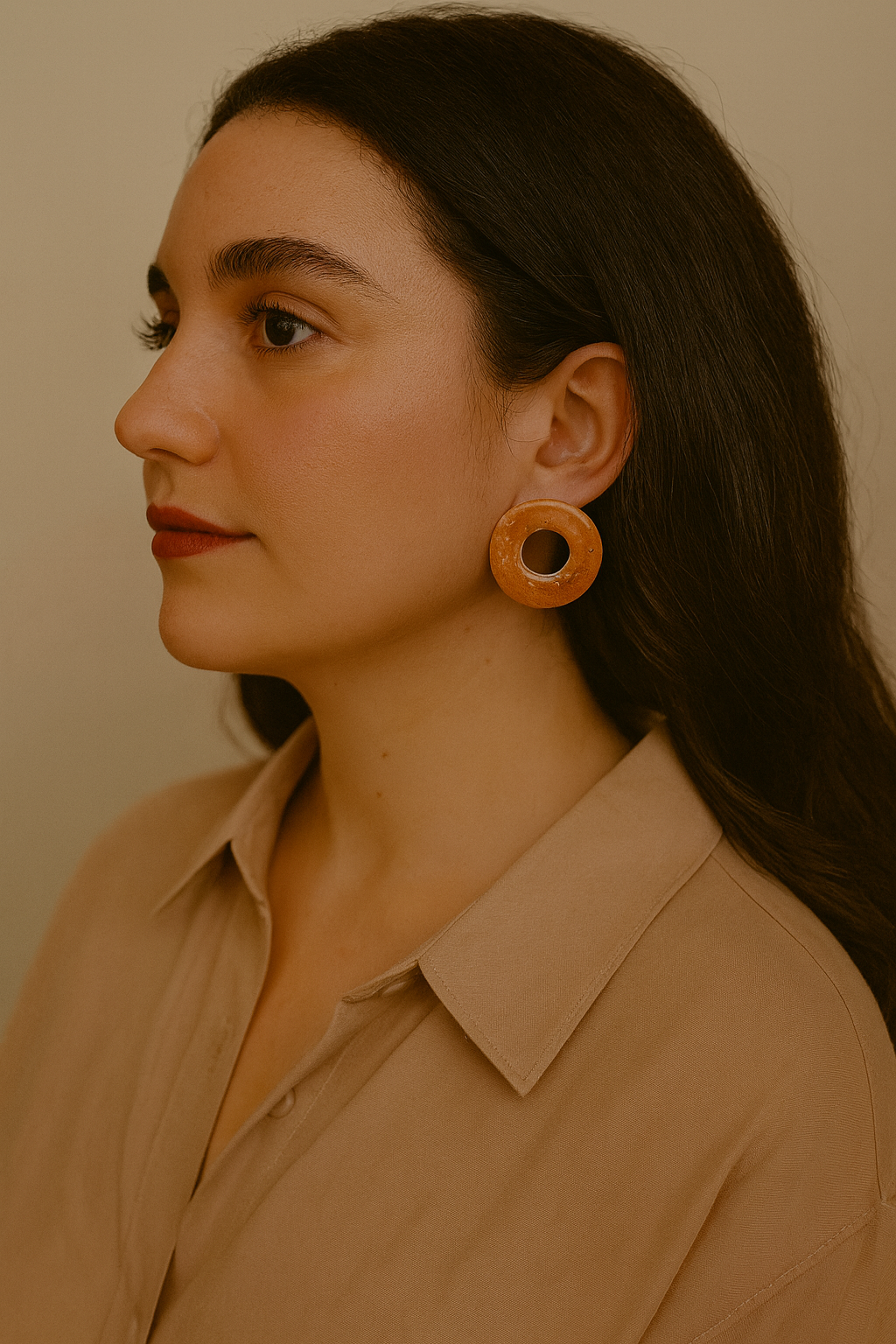 Woman wearing wooden earrings with a neutral background