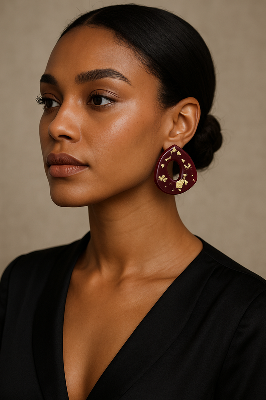 Woman wearing Apple Cider polymer clay stud earrings featuring deep red tones with shimmering gold flakes and a glossy resin glaze, inspired by fall doughnuts.