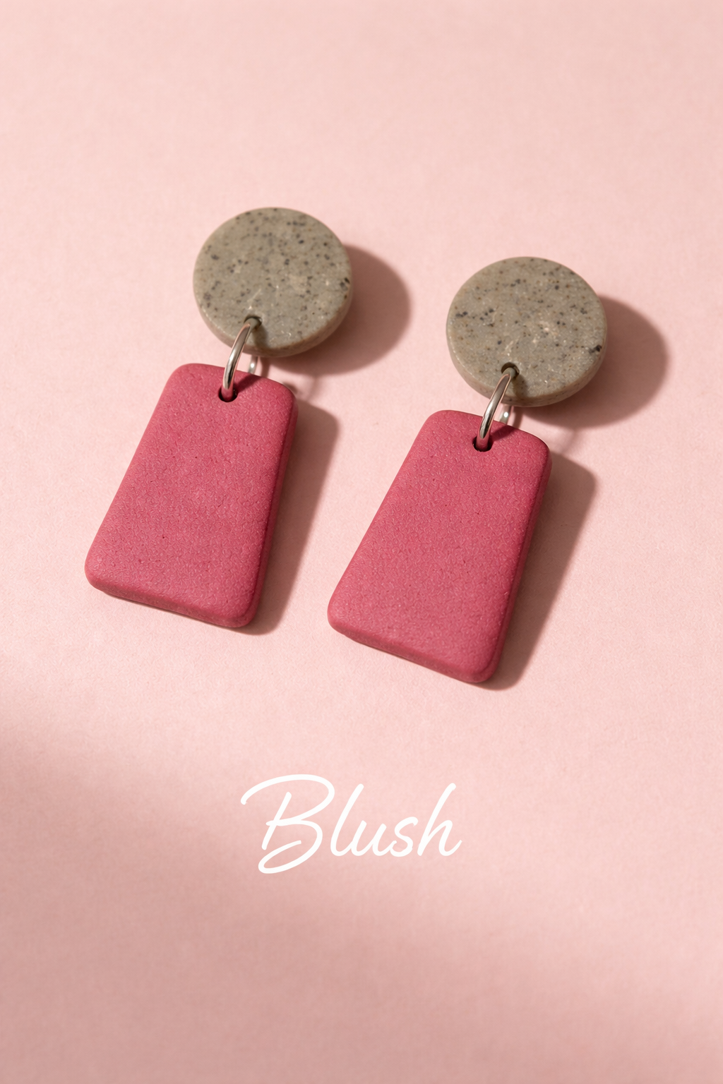 Pink earrings with concrete-like tops on a pink background.