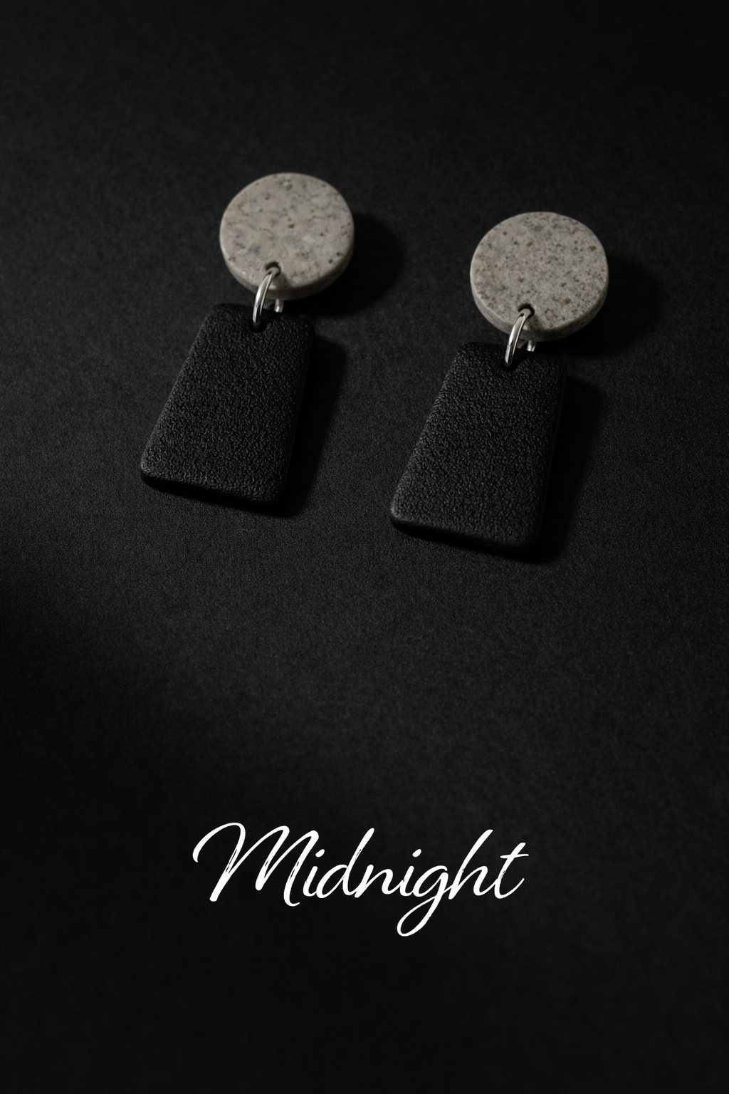 Black and grey earrings on a black background. 