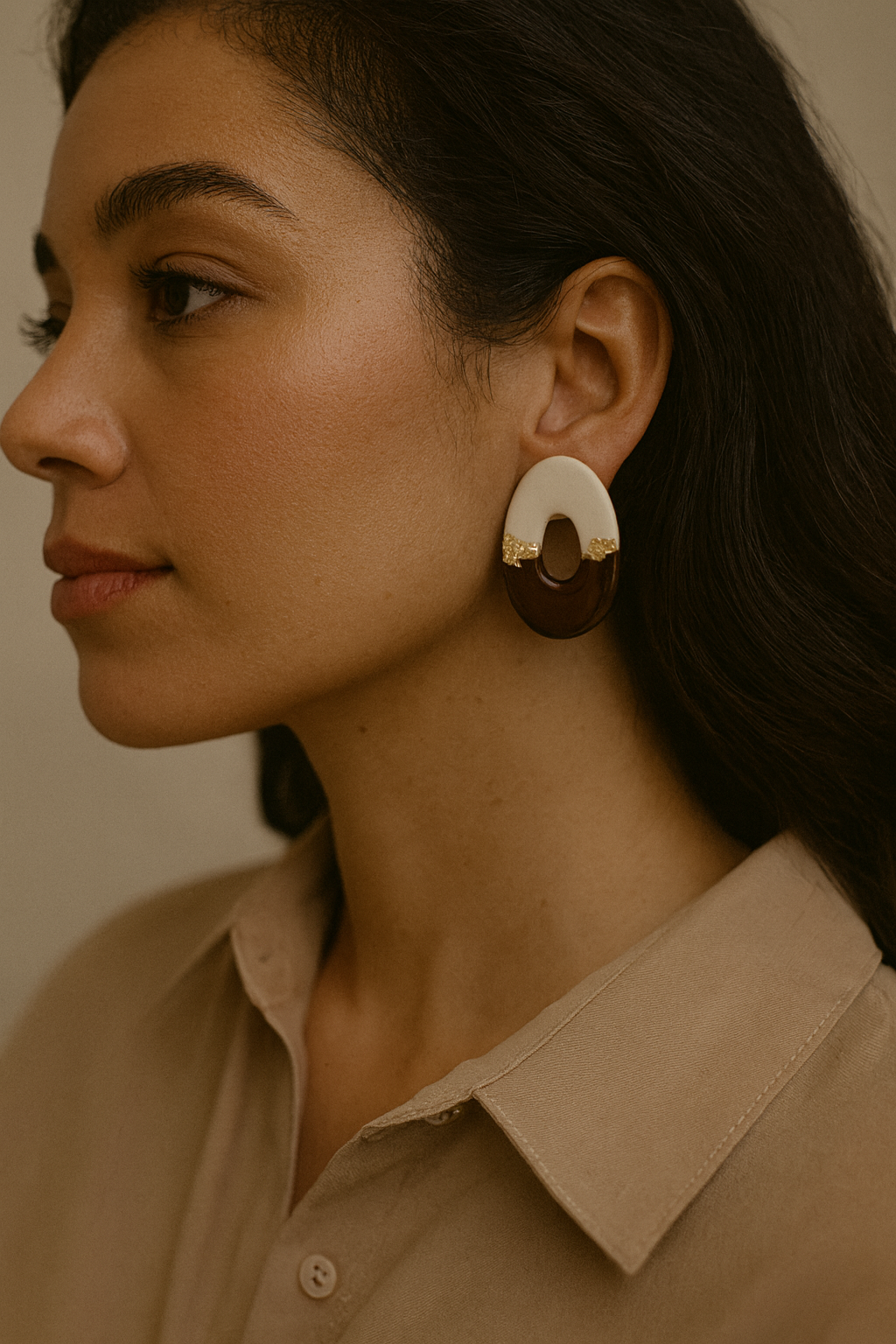 Close-up of a woman wearing a pair of earrings with a neutral background