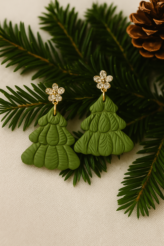 Green Christmas tree earrings with gold accents on a green leaf background
