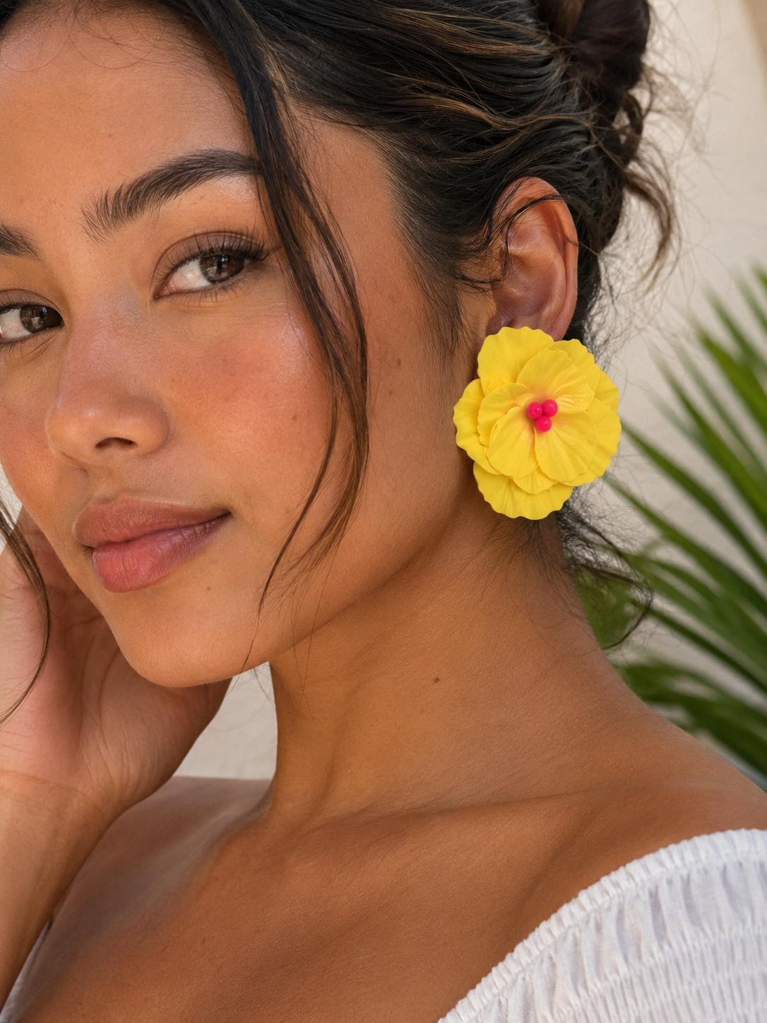 Woman wearing a yellow flower earring with a blurred natural background