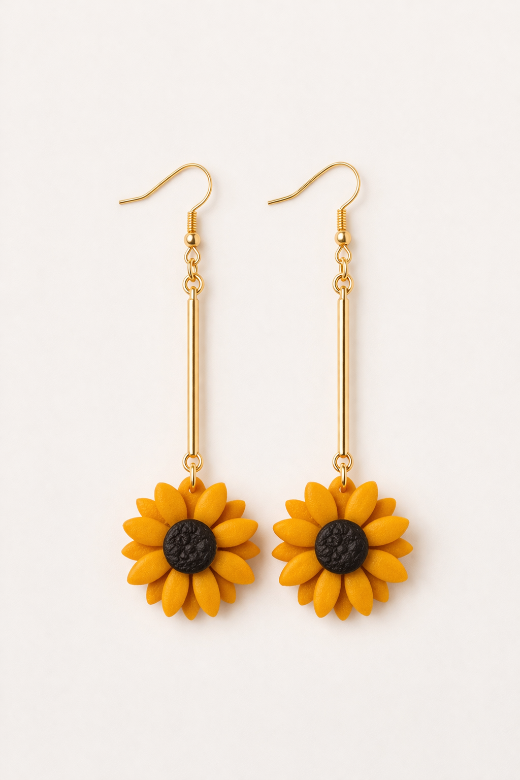 Golden sunflower polymer clay dangle earrings with yellow petals and gold bar detail on a neutral background