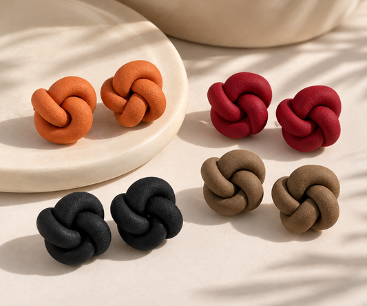 Different-colored knot earrings on simple background