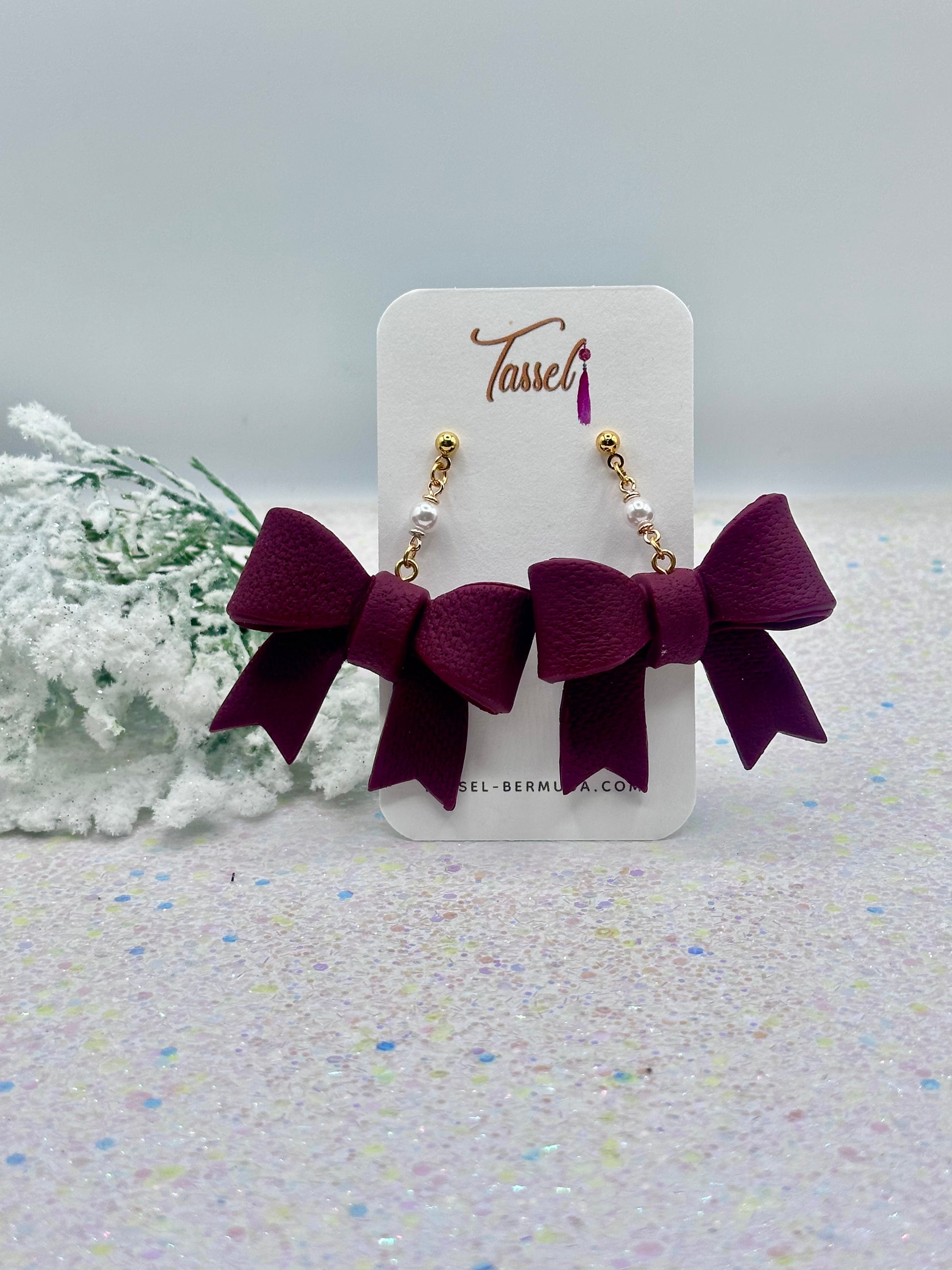 Pair of Burgundy bow earrings on a Tassel branded card with a light background