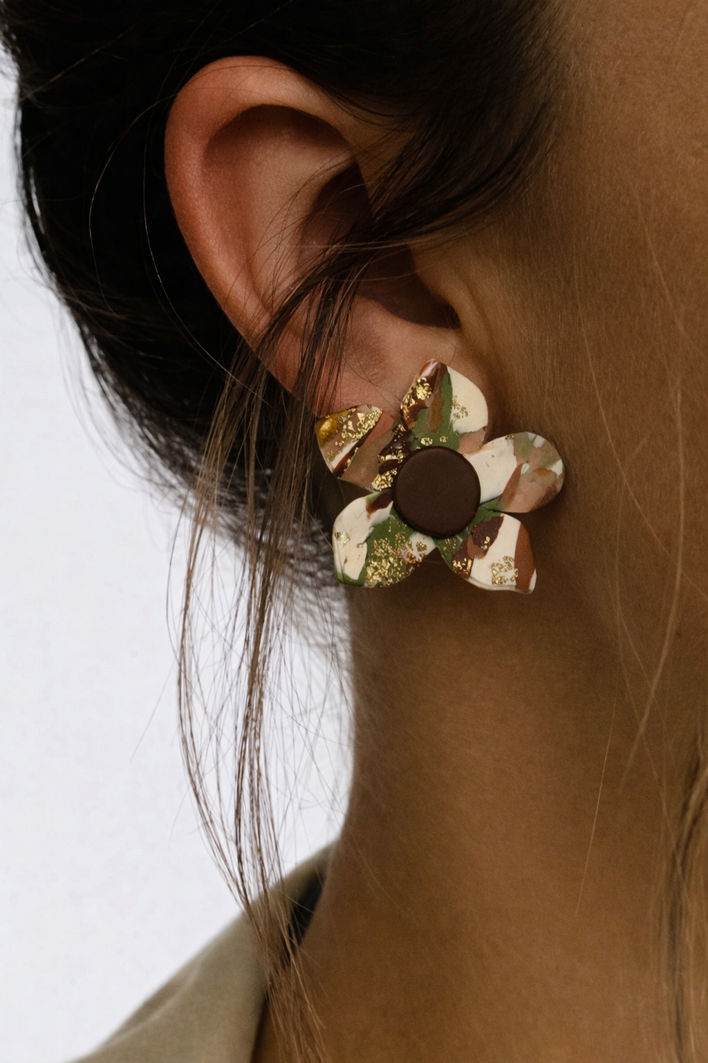 Close-up of a floral earring worn by a person with a neutral background