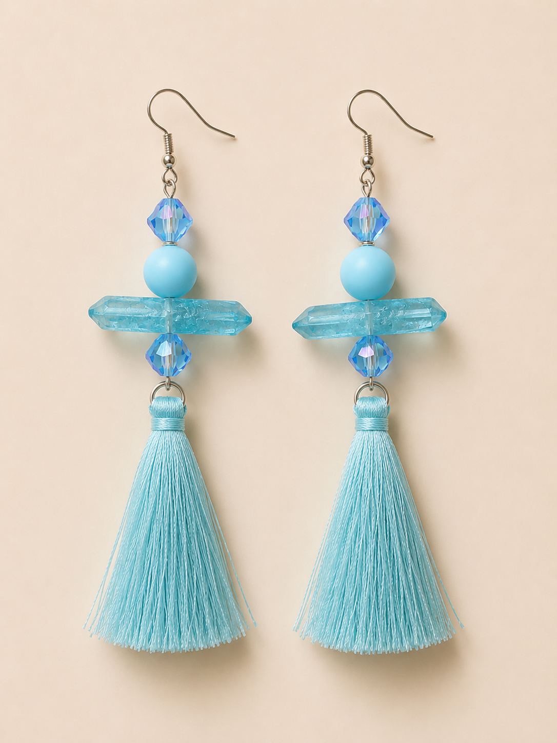 Pair of blue tassel earrings on a beige background