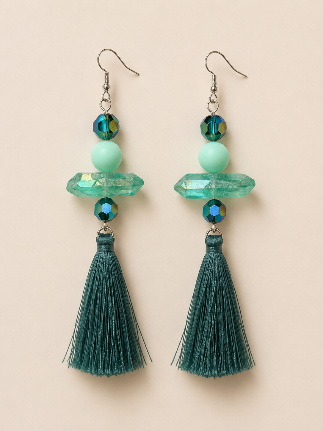 Green tassel earrings with beads on a beige background