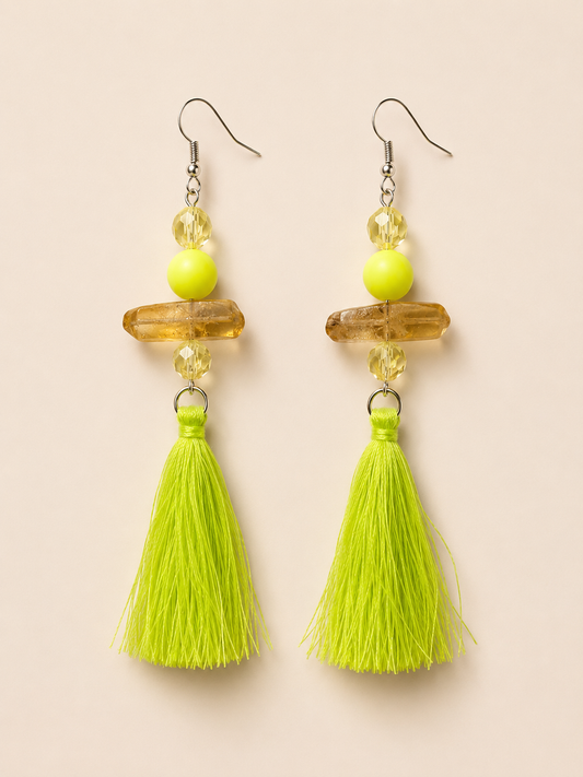 Pair of earrings with yellow beads and green tassels on a beige background