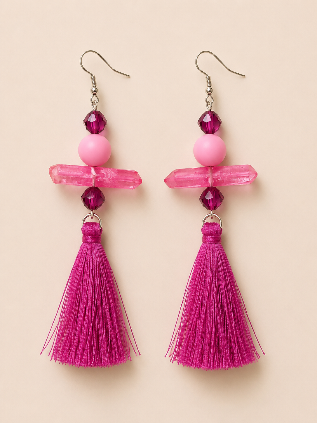 Pink tassel earrings with beads on a beige background