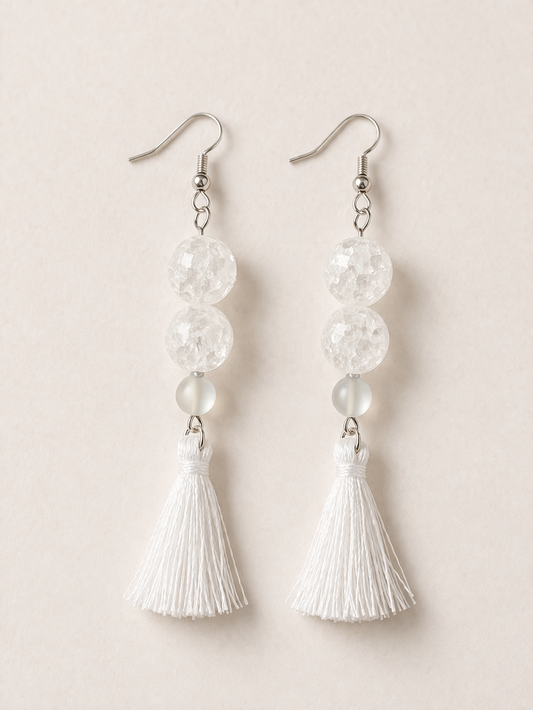 Salt Air dangle earrings with white tassels and translucent textured beads on a neutral background